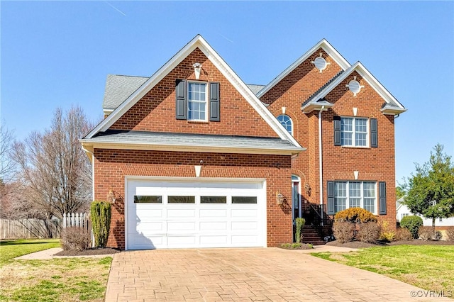 traditional-style house featuring decorative driveway, brick siding, a garage, and a shingled roof