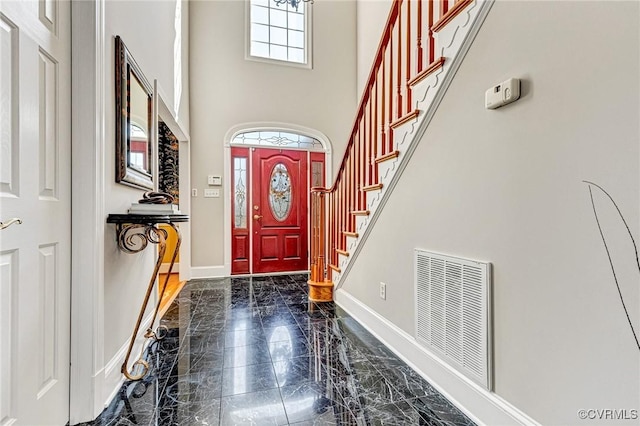 entrance foyer with stairway, visible vents, baseboards, a high ceiling, and marble finish floor