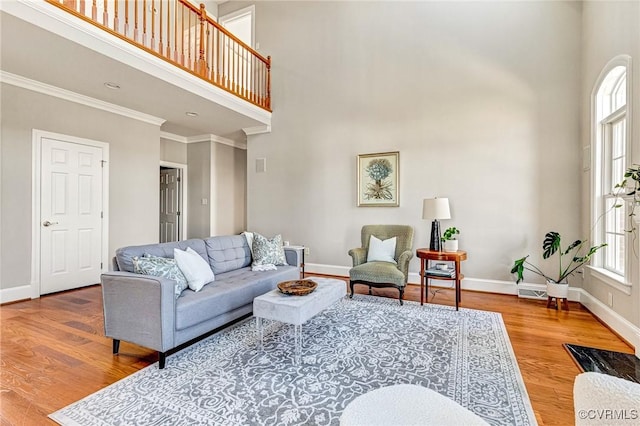 living area with crown molding, a high ceiling, wood finished floors, and baseboards