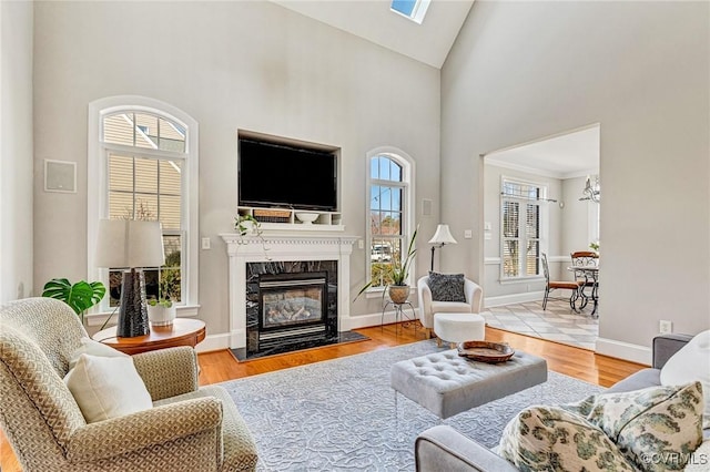 living room with a high end fireplace, high vaulted ceiling, baseboards, and wood finished floors