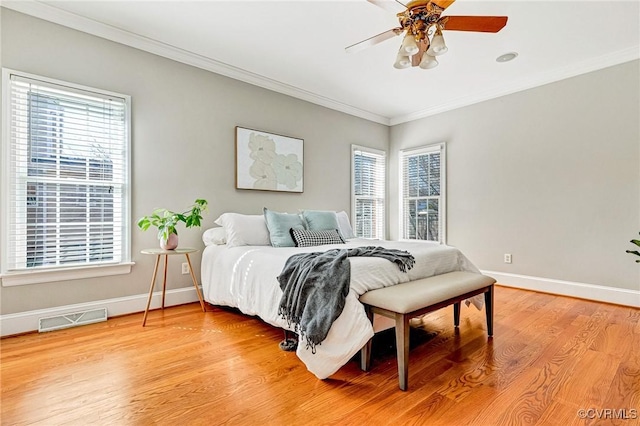 bedroom featuring baseboards, light wood-style floors, visible vents, and ornamental molding