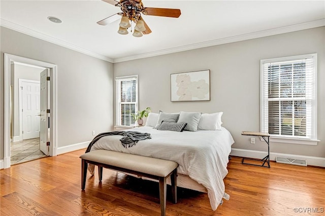 bedroom featuring visible vents, ornamental molding, light wood-style floors, baseboards, and ceiling fan