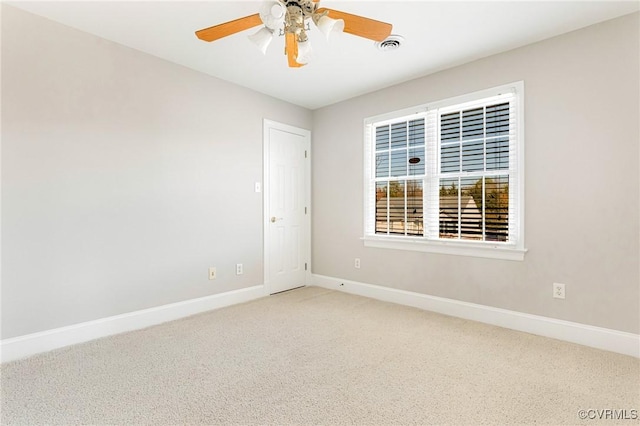 empty room featuring carpet flooring, visible vents, a ceiling fan, and baseboards