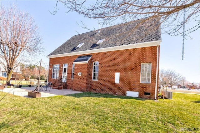 back of property featuring brick siding, a shingled roof, entry steps, a yard, and a patio