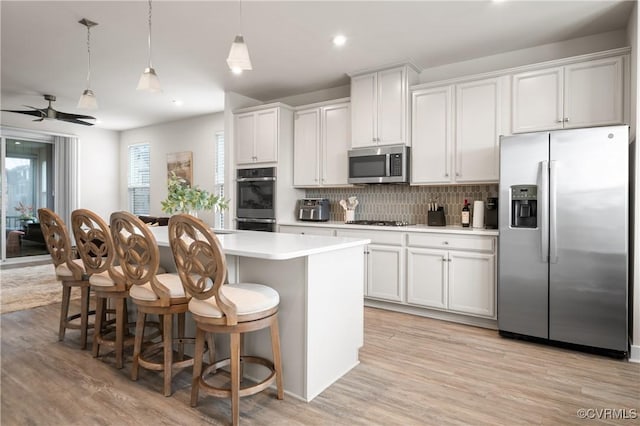 kitchen featuring decorative backsplash, a kitchen island, a breakfast bar area, stainless steel appliances, and light countertops