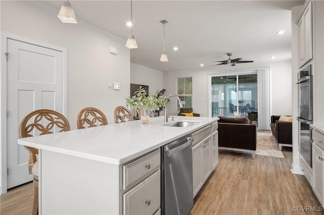 kitchen featuring appliances with stainless steel finishes, open floor plan, light countertops, and a sink