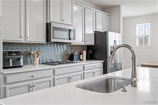 kitchen featuring backsplash, stainless steel appliances, a sink, and light countertops