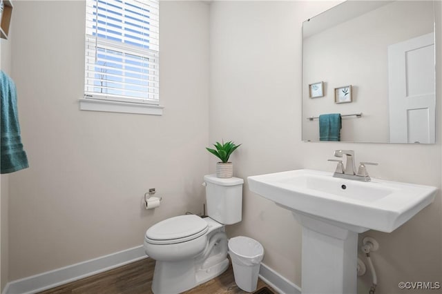 half bathroom with toilet, baseboards, and wood finished floors