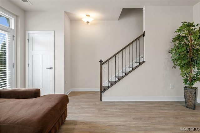 foyer entrance with stairs, baseboards, and wood finished floors