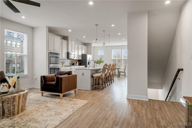 interior space featuring baseboards, a ceiling fan, light wood-style flooring, and recessed lighting