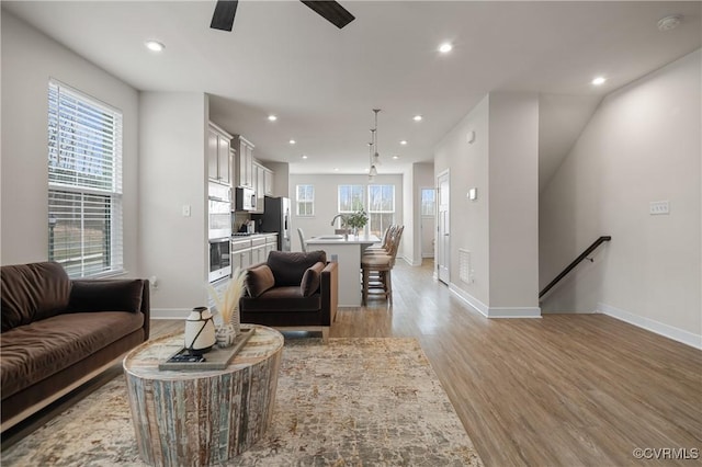 living area featuring light wood-type flooring, baseboards, a ceiling fan, and recessed lighting