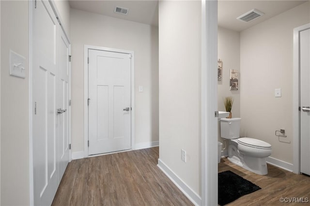 bathroom with toilet, wood finished floors, visible vents, and baseboards