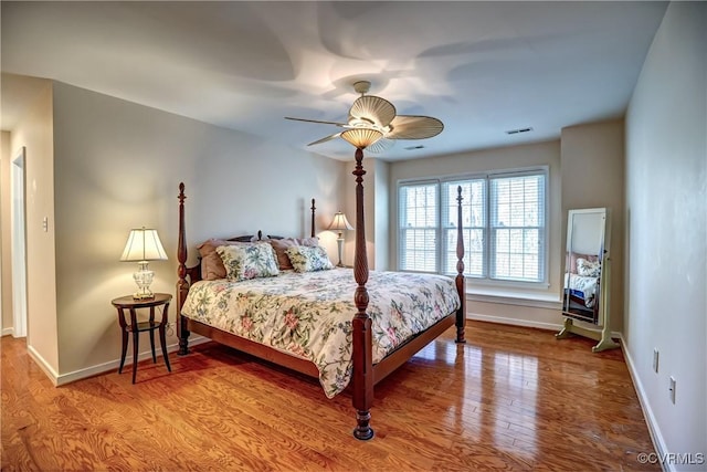 bedroom with baseboards, visible vents, ceiling fan, and wood finished floors