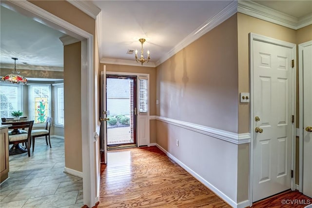 foyer featuring a chandelier, a healthy amount of sunlight, and ornamental molding