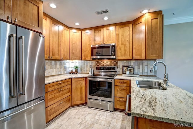 kitchen with appliances with stainless steel finishes, visible vents, a sink, and backsplash