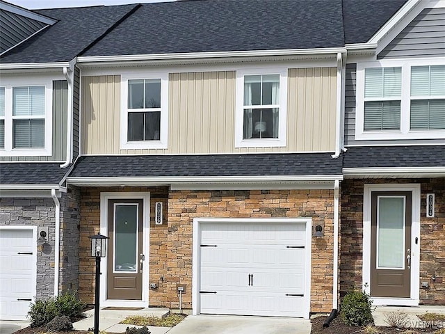 view of property featuring a garage, stone siding, and a shingled roof