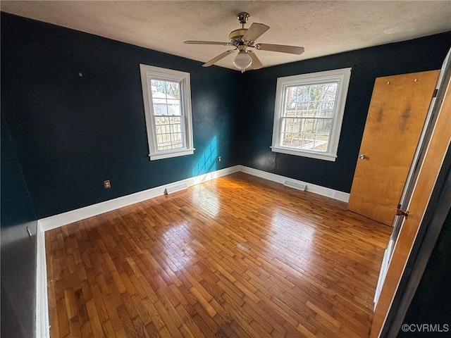 unfurnished room featuring a wealth of natural light, a textured ceiling, and hardwood / wood-style floors