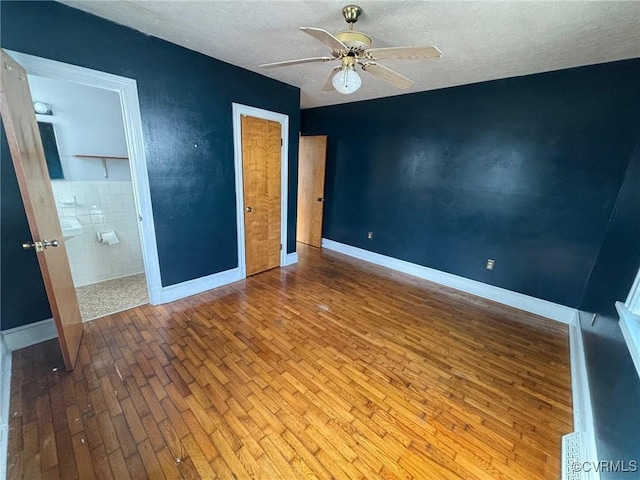 unfurnished bedroom with connected bathroom, ceiling fan, a textured ceiling, and wood finished floors