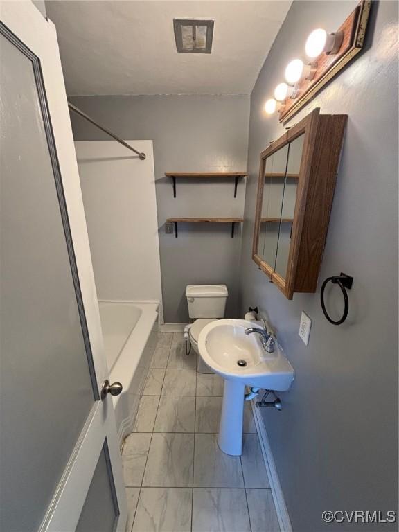 bathroom featuring toilet, a sink, bathing tub / shower combination, baseboards, and marble finish floor