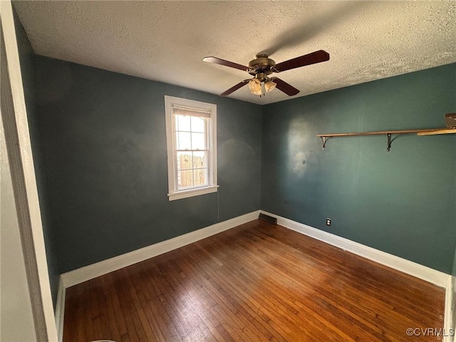 spare room featuring dark wood-style flooring, ceiling fan, a textured ceiling, and baseboards