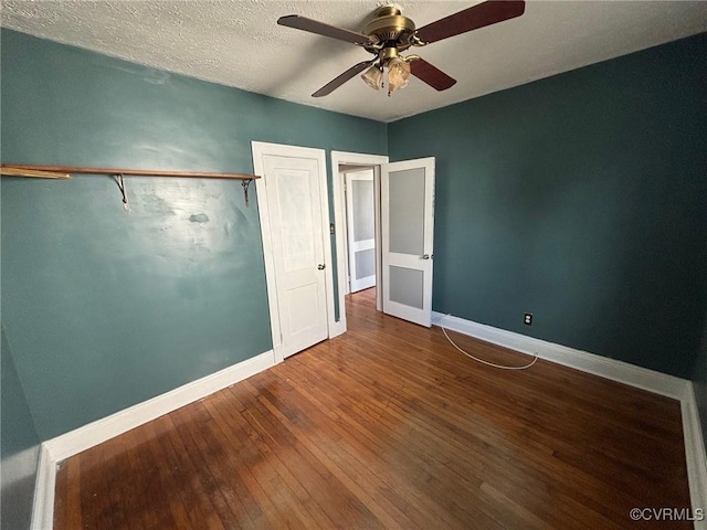 unfurnished bedroom featuring hardwood / wood-style flooring, a ceiling fan, baseboards, and a textured ceiling