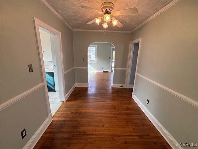 hall featuring ornamental molding, arched walkways, a textured ceiling, and wood finished floors