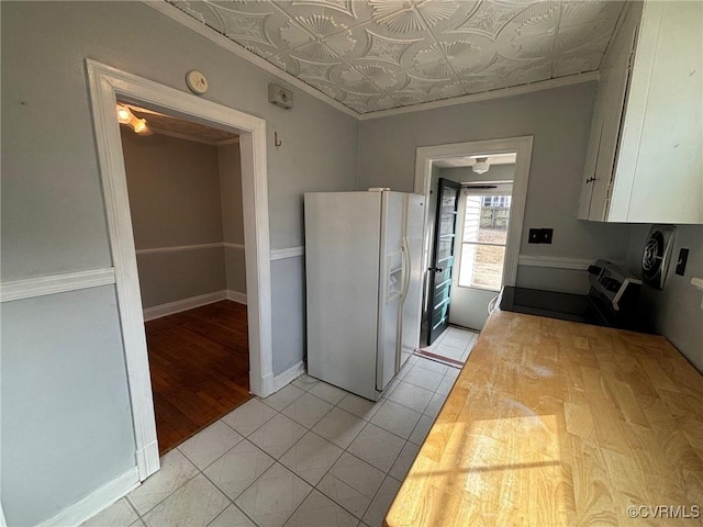 kitchen featuring an ornate ceiling, range with electric stovetop, light tile patterned floors, white cabinetry, and white fridge with ice dispenser