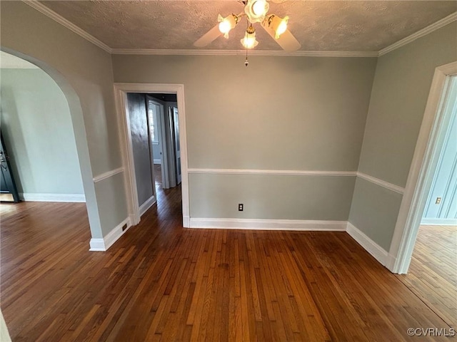 spare room featuring arched walkways, hardwood / wood-style floors, a textured ceiling, and baseboards