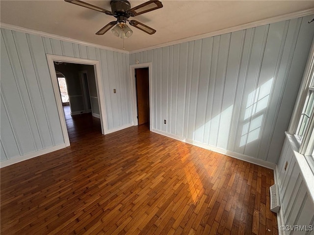 empty room featuring visible vents, baseboards, a ceiling fan, dark wood finished floors, and crown molding