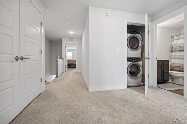 laundry area featuring laundry area, baseboards, stacked washer / drying machine, and carpet flooring