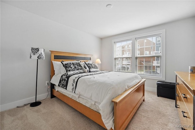 bedroom with baseboards and light colored carpet