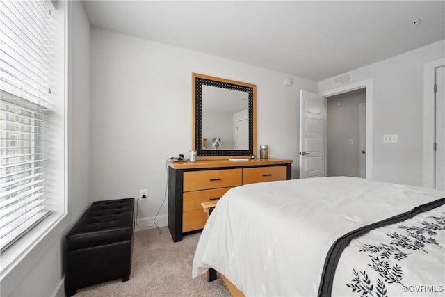 bedroom with visible vents, light carpet, and baseboards