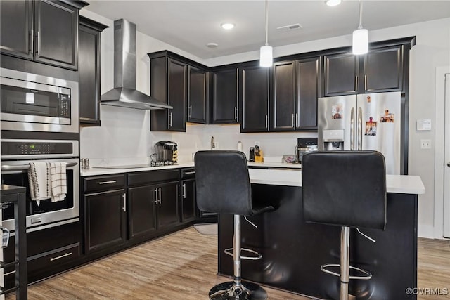 kitchen featuring wall chimney exhaust hood, visible vents, stainless steel appliances, and light countertops