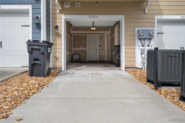 property entrance featuring a garage, cooling unit, and driveway