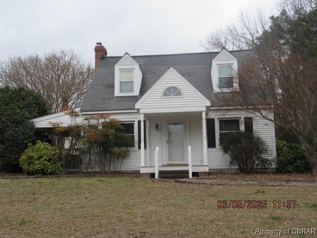 new england style home with a chimney and a front lawn