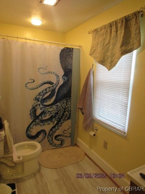 bathroom featuring toilet and curtained shower