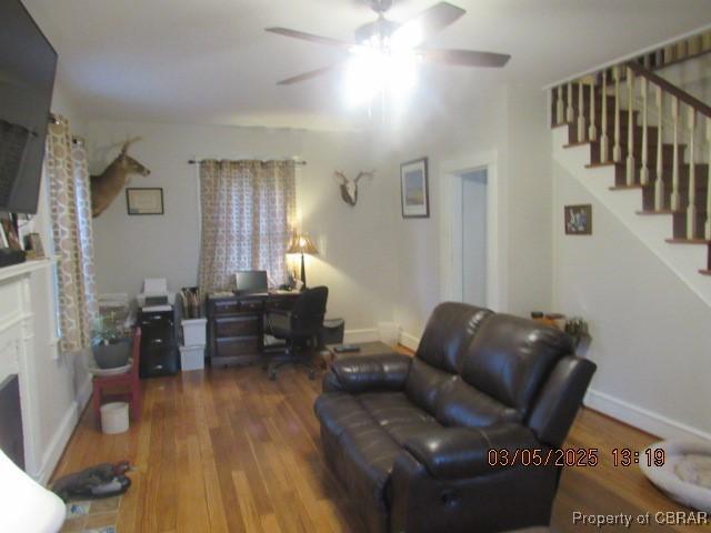 living area featuring stairs, a fireplace, baseboards, and wood finished floors