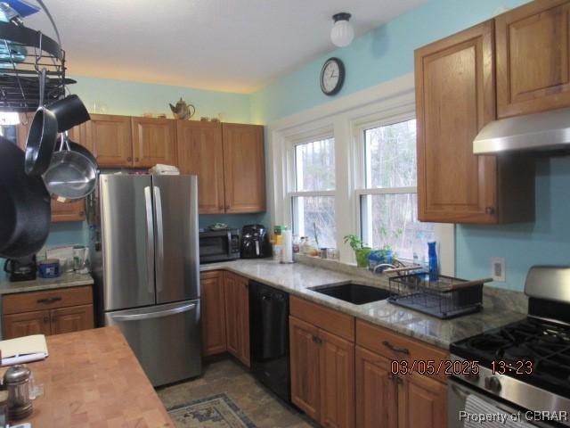 kitchen with stainless steel appliances, under cabinet range hood, a sink, and brown cabinets