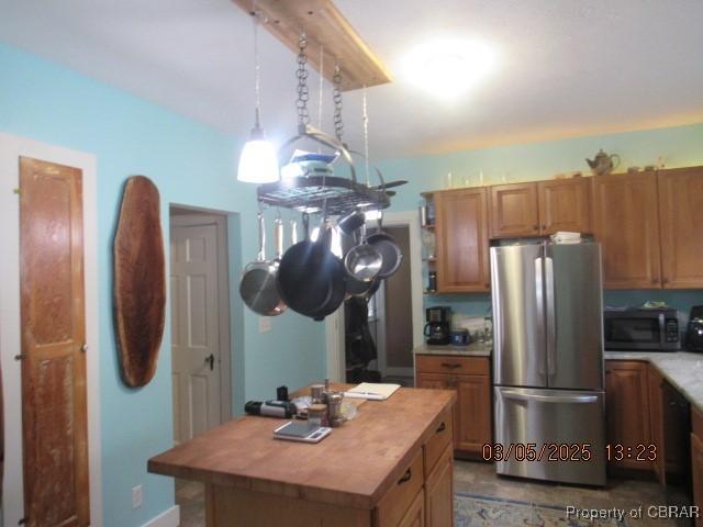 kitchen with a center island, stainless steel appliances, butcher block counters, hanging light fixtures, and brown cabinetry