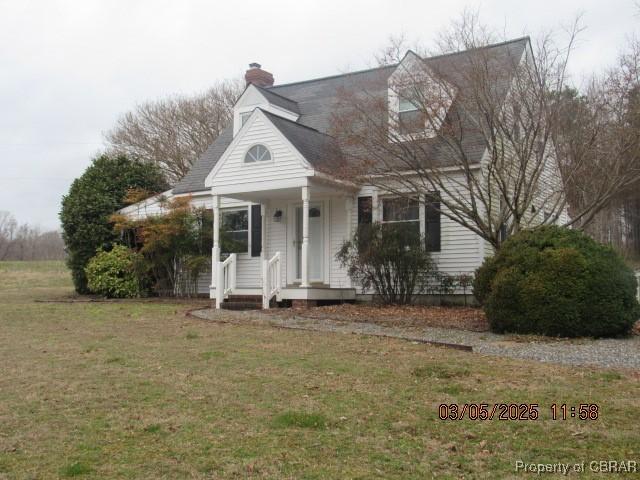 cape cod-style house with a chimney and a front lawn
