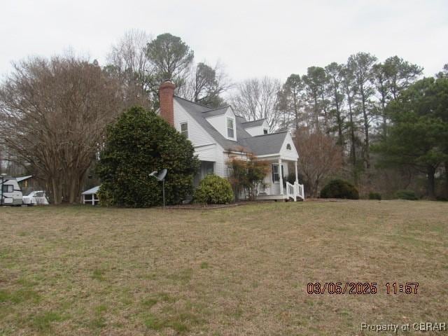 view of side of property featuring a lawn and a chimney