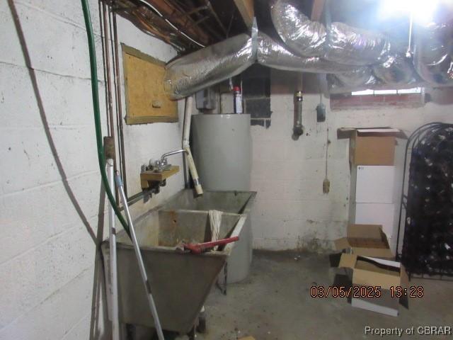unfinished basement with concrete block wall, heating fuel, and water heater