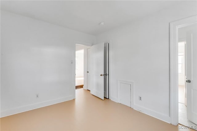 empty room with concrete flooring and baseboards