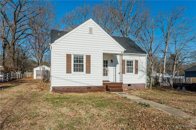 bungalow with a shingled roof, crawl space, fence, and a front lawn