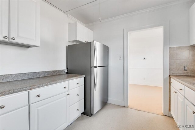 kitchen with light countertops, freestanding refrigerator, white cabinets, and crown molding