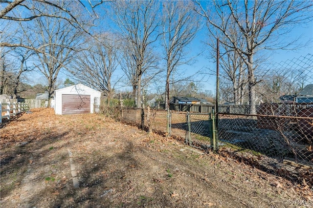 view of yard featuring an outbuilding, a fenced backyard, a detached garage, driveway, and a shed