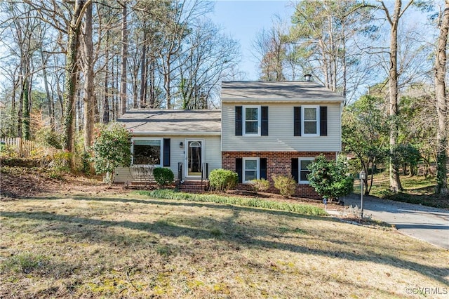 tri-level home featuring a front yard and brick siding