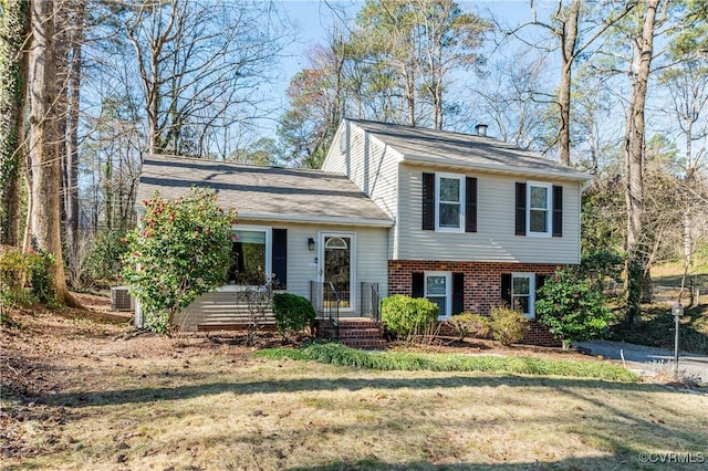 split level home featuring a front lawn and brick siding