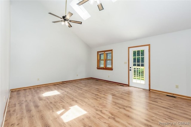 spare room featuring a skylight, ceiling fan, wood finished floors, high vaulted ceiling, and baseboards