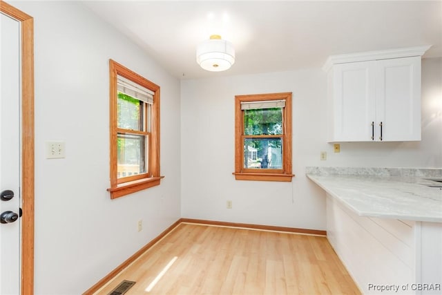 unfurnished dining area featuring light wood finished floors, visible vents, and baseboards